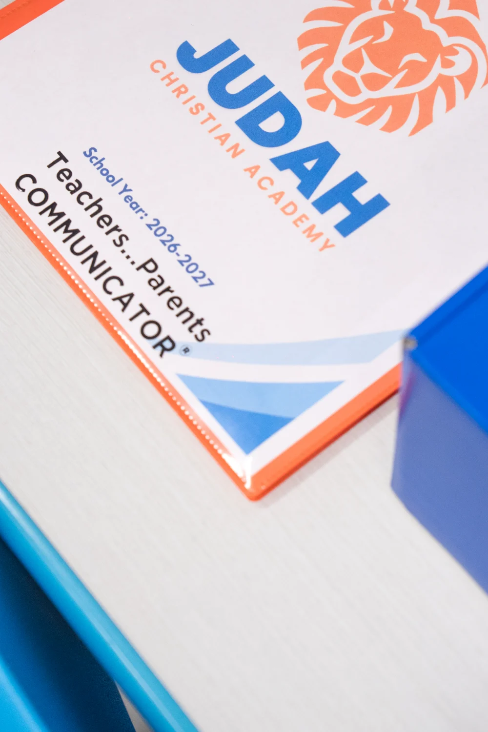 Close-up of a Judah Christian Academy folder showing the lion logo.