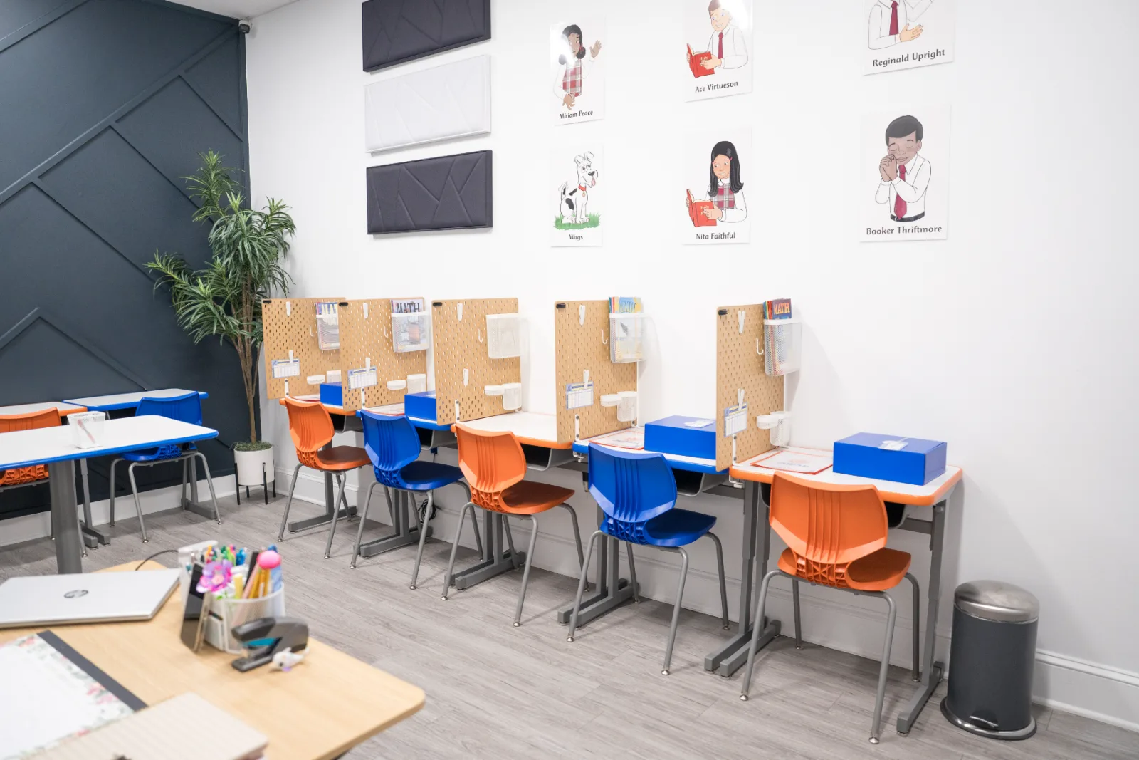 A Judah Christian Academy classroom with work tables and orange and blue chairs.
