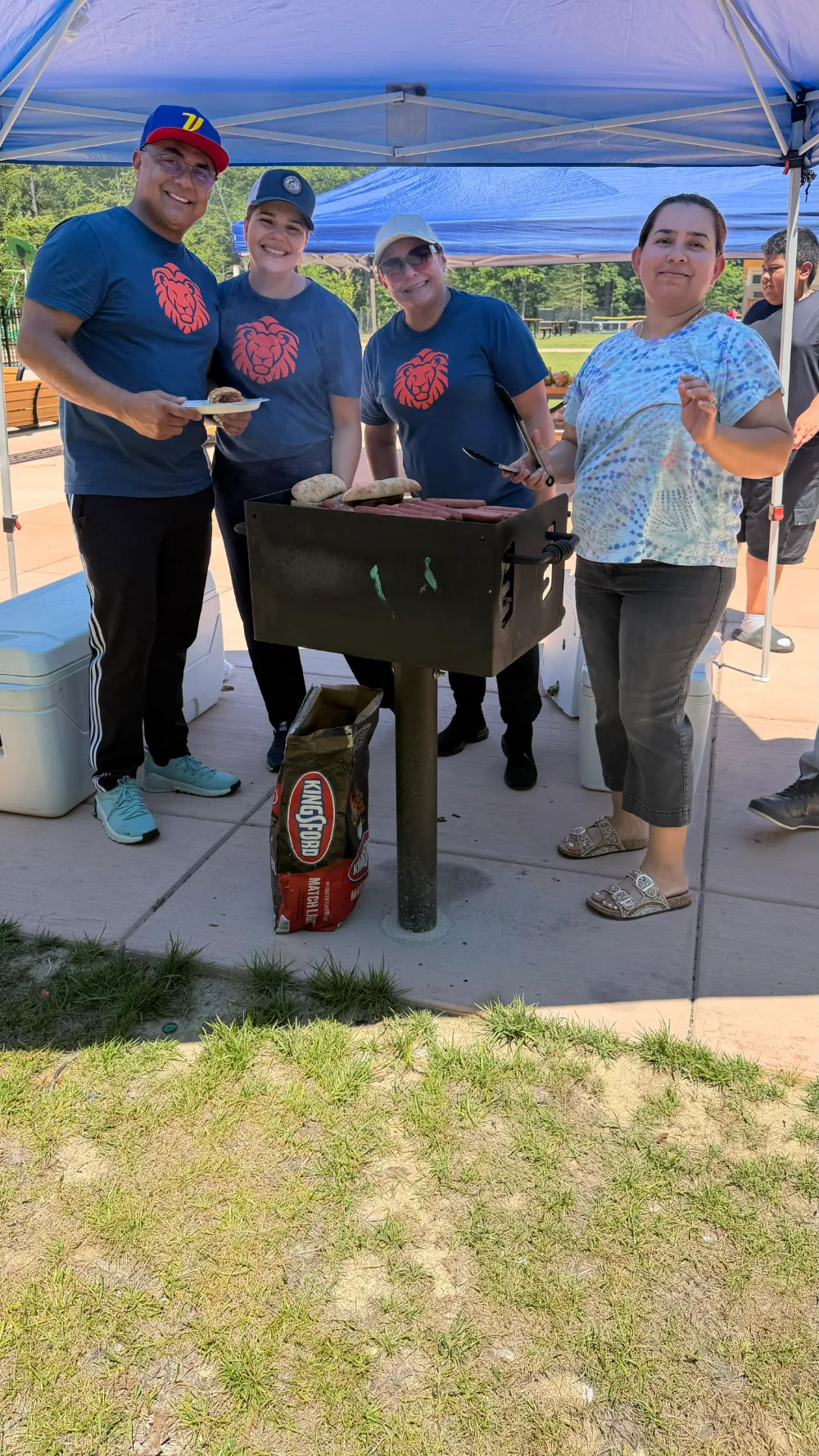 Adults preparing food under a canopy at a community gathering.