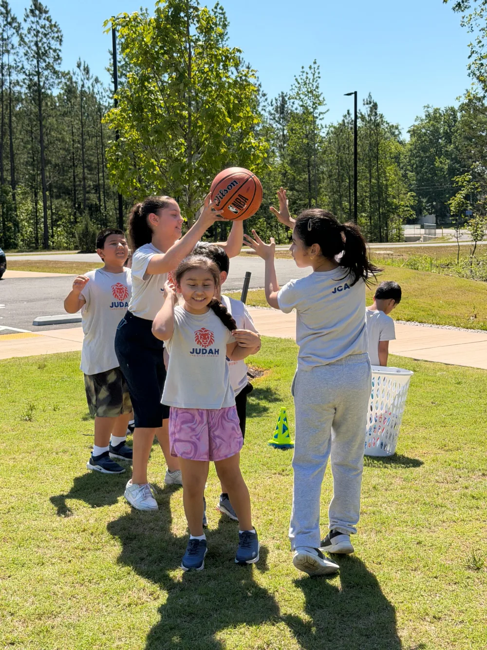 Students playing basketball together on an outdoor court.