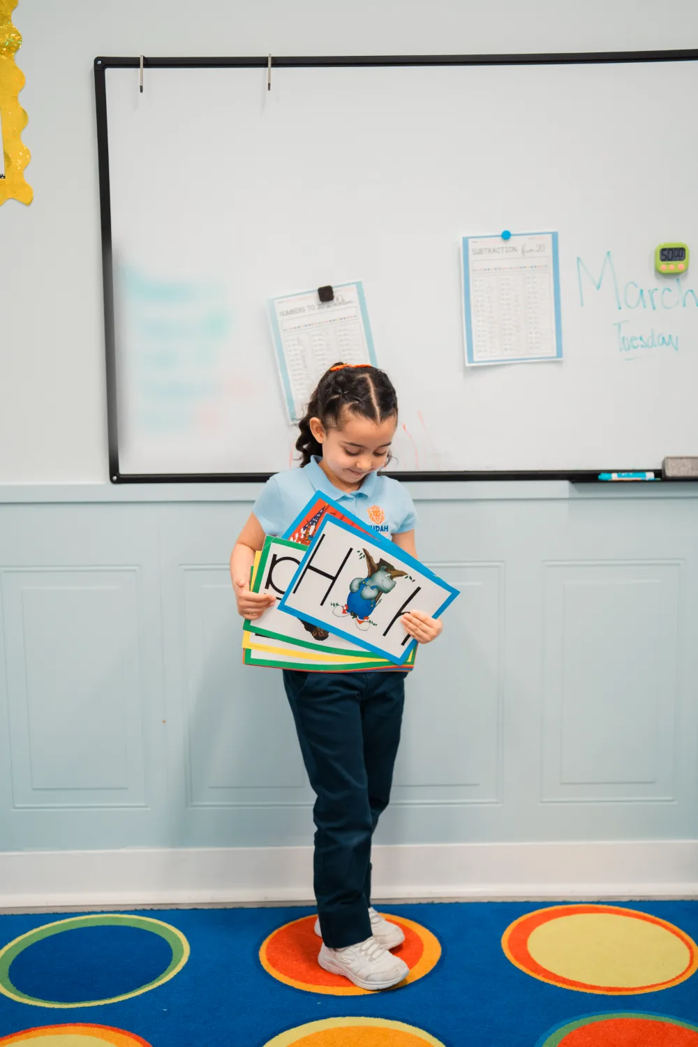 A student at the classroom whiteboard holding learning cards.