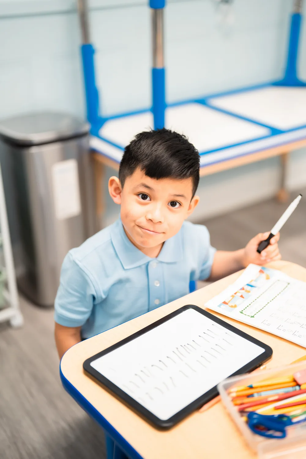 A Judah Christian Academy student holding a pencil at their desk.